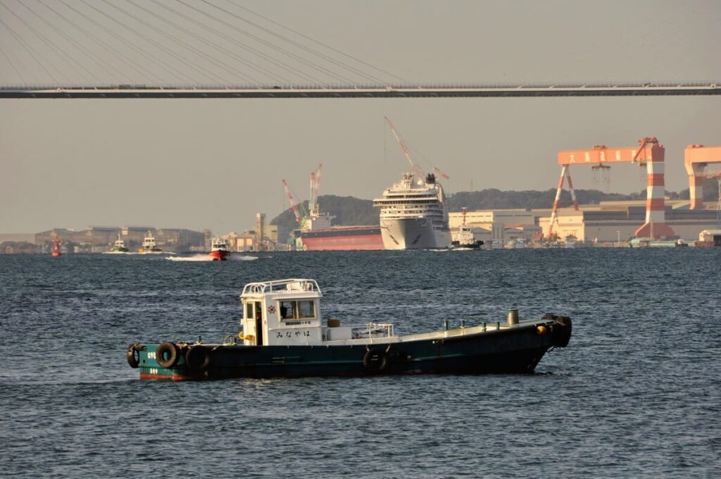 女神大橋を背に、シーボーン・アンコールをエスコートする赤いパイロット船の疾走